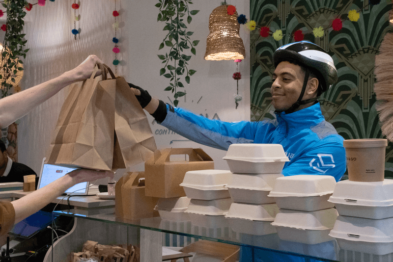Black male courier receiving 2 paper bags in a restaurant